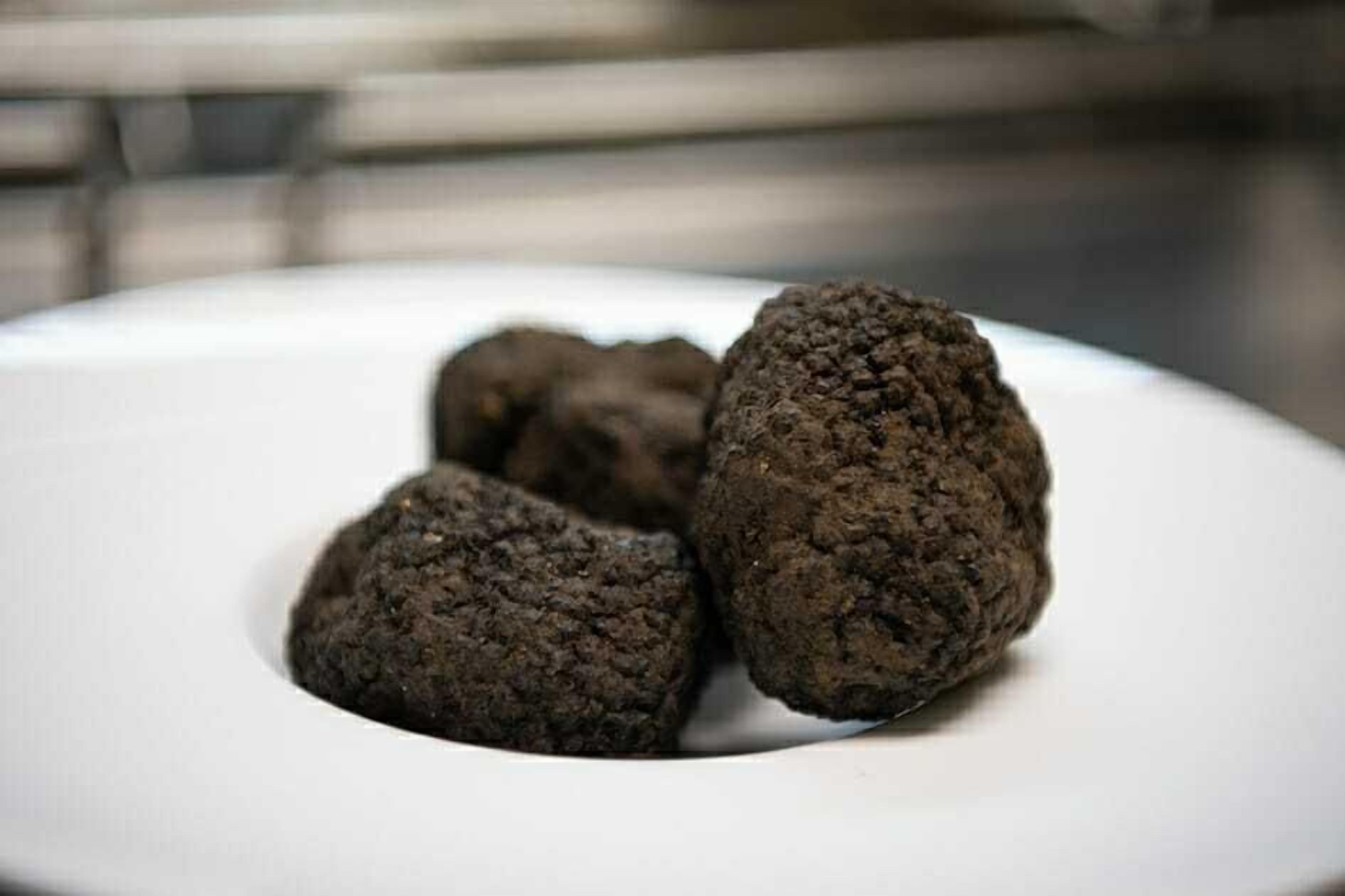 En tallrik med tre mörkbruna föremål som har en tydlig yta.