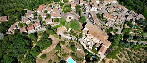 Vista aérea de una zona residencial con casas, una plaza circular central y una piscina.