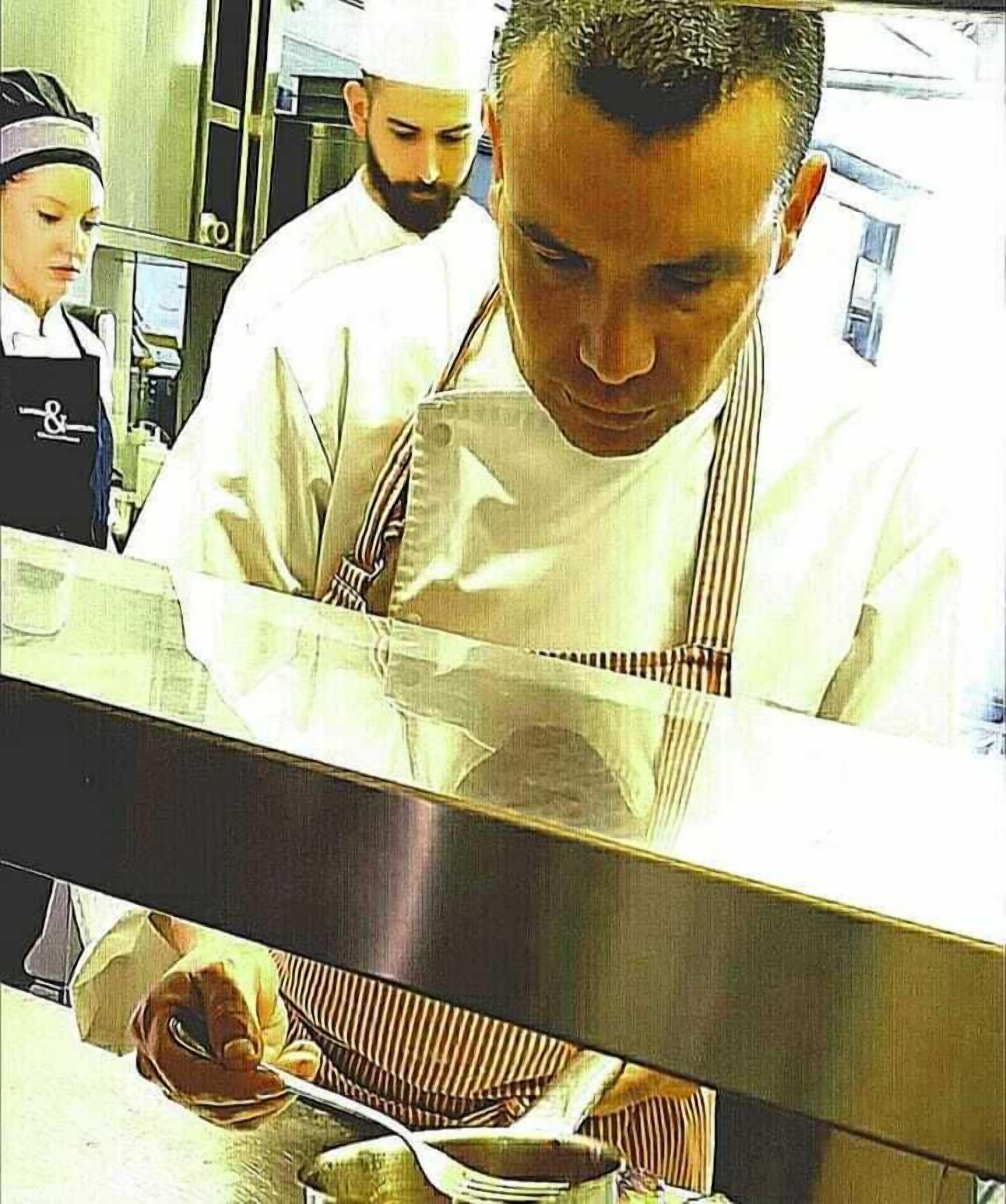 Un chef en una cocina profesional con superficies de acero inoxidable y un revoque reflectante.