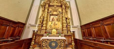 Un altar ornamentado con estatuas religiosas y una figura central, rodeado de paneles de madera.