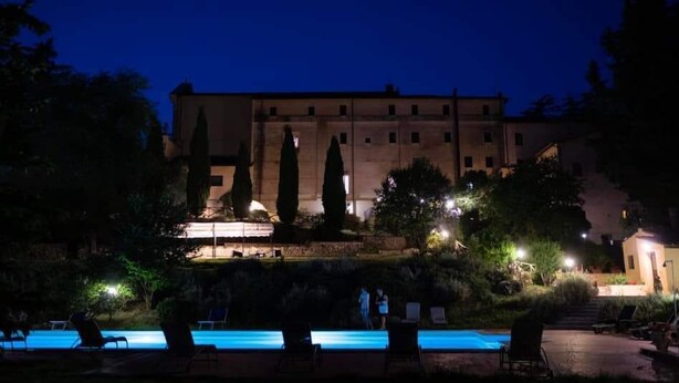 Un edificio con piscina y sillones de descanso al frente.