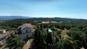 Vista de un paisaje rural con una iglesia, una piscina y vegetación circundante.