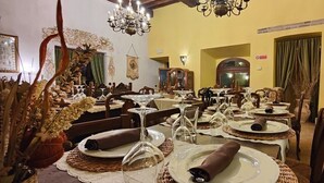 Un comedor con varias mesas dispuestas para una comida, con cristalería transparente y servilletas dobladas con cuidado.
