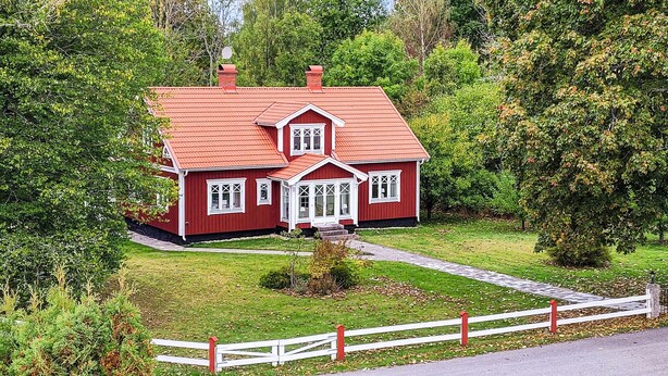Ein rotes Haus mit weißem Veranda und kleinem Vorgarten.