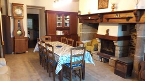 Un comedor con una mesa y sillas de madera, una estantería empotrada, una chimenea y un reloj en la pared.