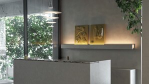 Un mostrador de recepción moderno con diseño minimalista, un amplio ventanal con vistas a zonas verdes y una lámpara fijada a la pared.