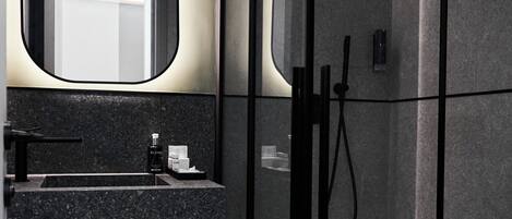 Un baño moderno con cabina de ducha de vidrio, un lavamanos con espejo y un inodoro.