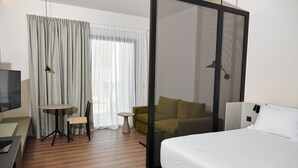 Una habitación de hotel con una cama, un escritorio, una silla, una mesita y un sofá.