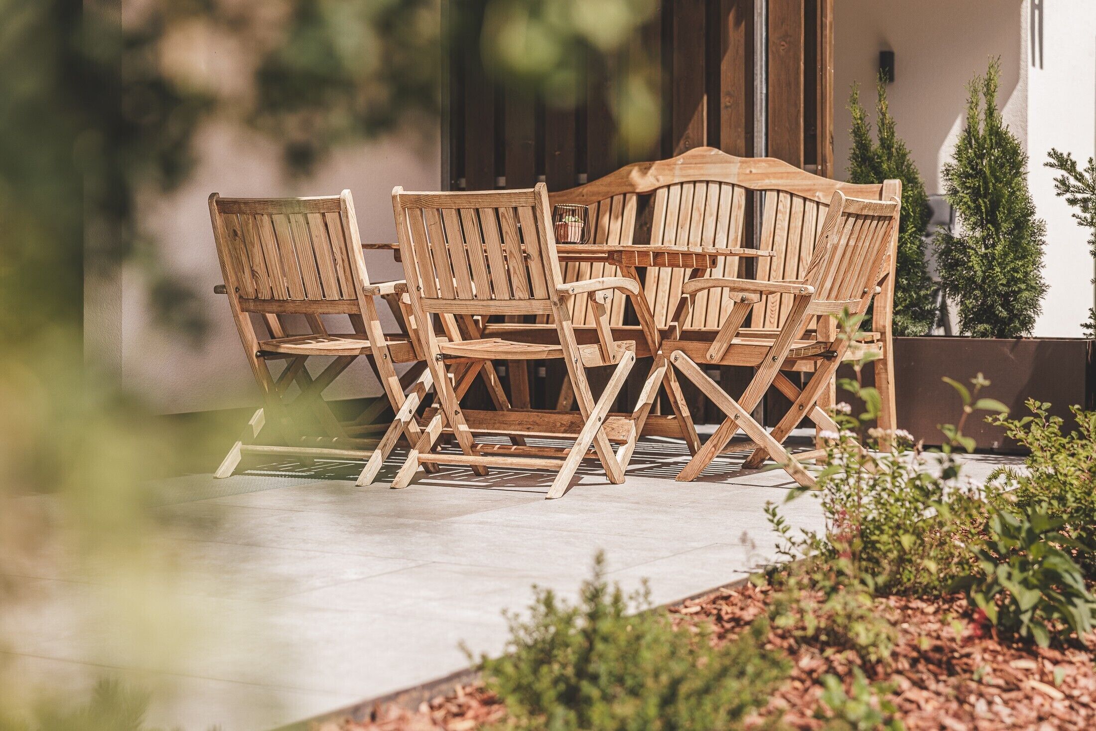 Un espace extérieur aménagé avec des meubles en bois, comprenant une table et des chaises.