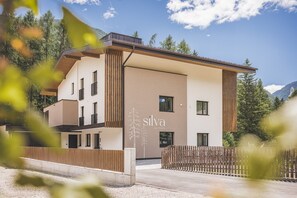 Ein modernes Gebäude mit einem Schild, auf dem 'silva apartments' steht, und einem Holzzaun davor.