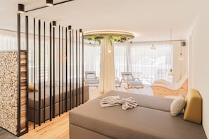 A modern hotel room with a sofa, a decorative plant, a wooden floor, and a view of the outside. - Silva Apartments - Apartment "Timeout" (San Giovanni)
