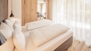 Une chambre à coucher moderne avec un grand lit, un lambris en bois et une vue sur l’extérieur.
