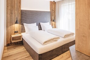 Un lit double avec une tête de lit en bois, des tables de chevet avec des lampes et un plancher en bois.