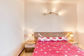 Una camera da letto con un letto, due comodini, una lampada a parete e un tavolino di appoggio.