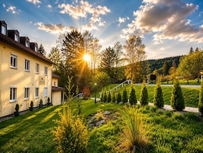 Um hotel com um jardim bem cuidado, uma escadaria que leva à entrada e uma vista ampla da paisagem ao redor.