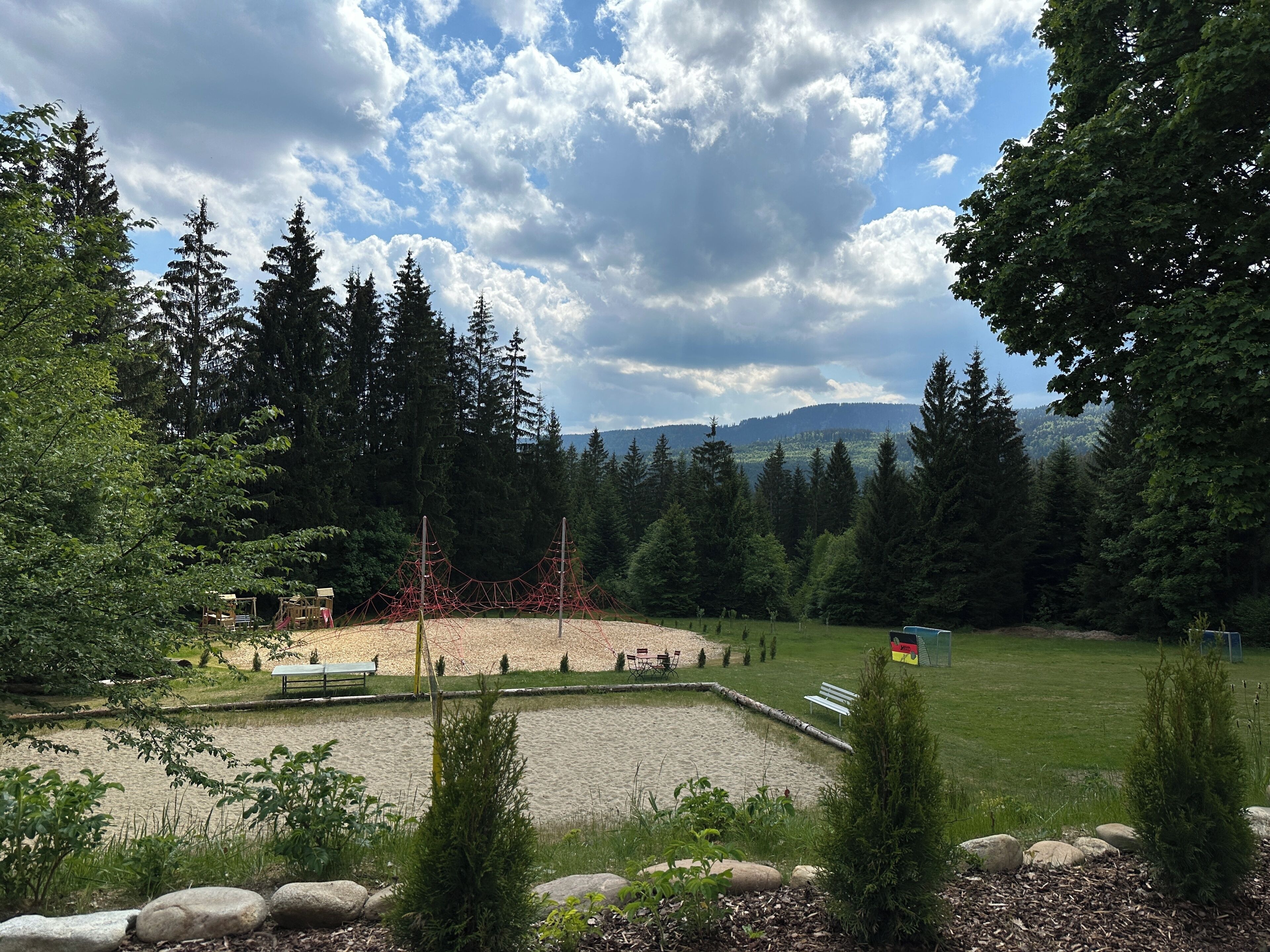 Un parque con un área de juegos, bancos y un estanque.