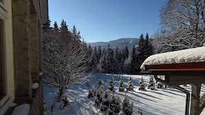 Paisaje nevado con un edificio, árboles cubiertos de nieve y cielo despejado.