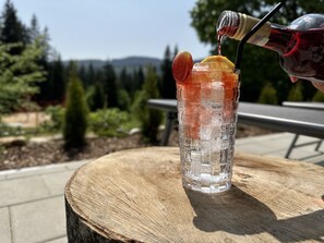 Un vaso de bebida helada adornado con una rodaja de limón sobre una superficie de madera al aire libre.