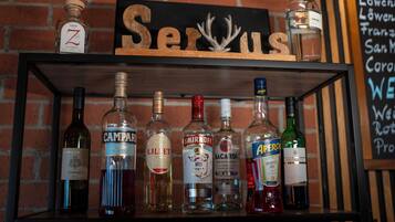 Una estantería con varias botellas de licor y un cartel que dice 'Servus'.