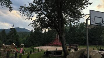 Ein Spielplatz mit Basketballkorb, Schaukeln und einer Rutsche.