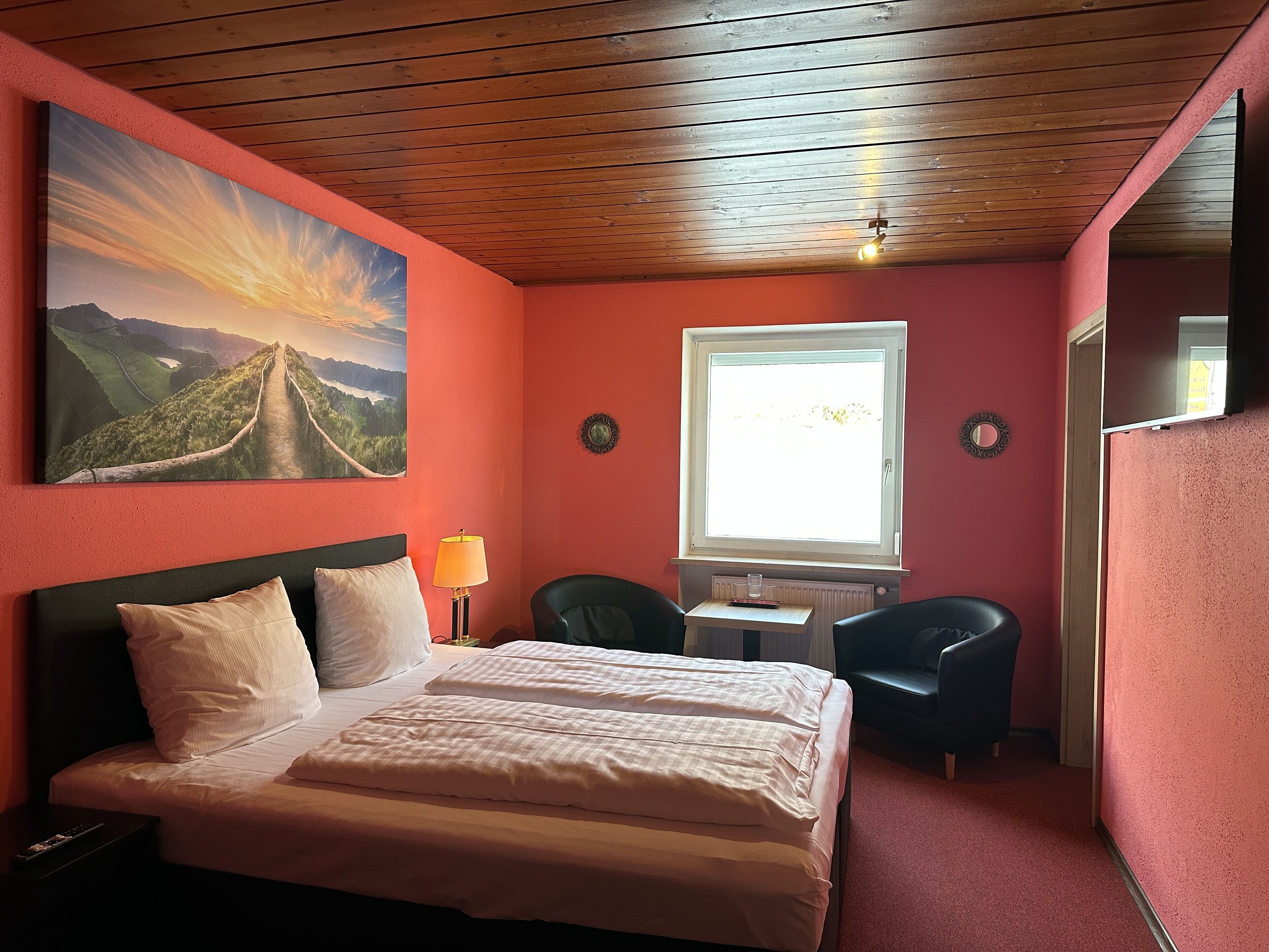 Une chambre à coucher avec un lit, un bureau, une chaise, une fenêtre et un tableau au mur.