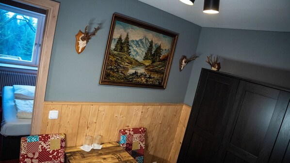 A room with a wooden bench, a painting of a mountain landscape, and antlers on the wall.
