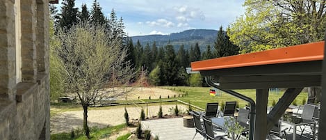 Un patio con mobiliario exterior y vistas a un viñedo y montañas.
