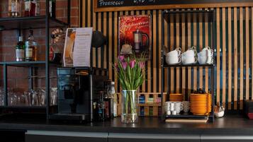 A bar area with a coffee machine, a menu board, and a variety of bottles and glasses.