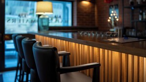 Zona de bar con paneles de madera, taburetes y una pantalla de televisión al fondo.