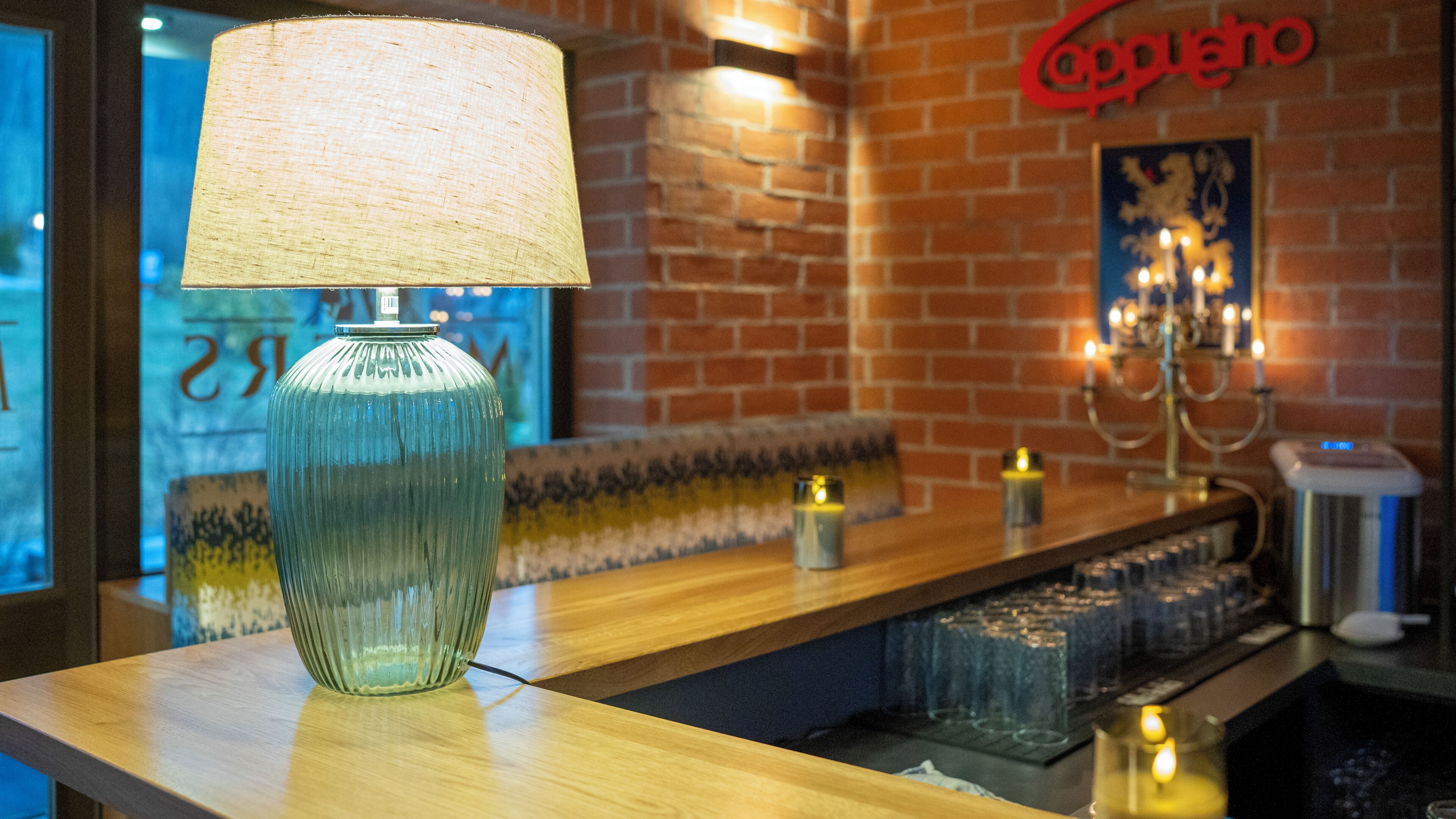 Zona de bar con una lámpara, una pared de ladrillo y un letrero que dice 'Coppio'.