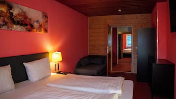 A hotel room with a bed, a nightstand, a lamp, a chair, and a painting on the wall.