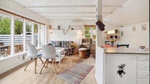 A spacious living area with a sofa, chairs, a dining table, and a kitchen area with a counter and cabinets.
