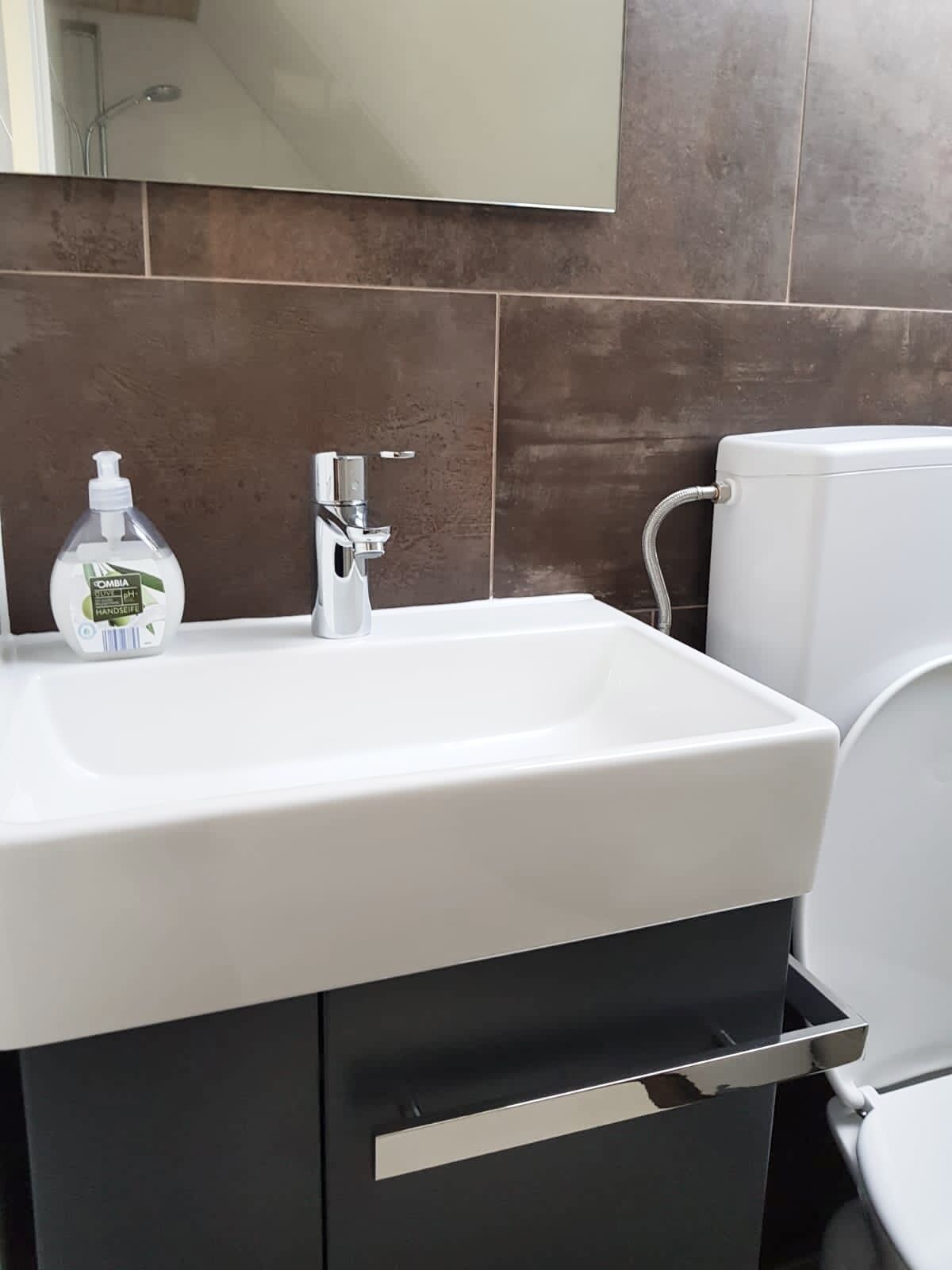 A bathroom with a white sink, a mirror, and a toilet.