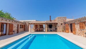 A poolside area with stone buildings, a pool, and a covered seating area. - Villa 'Hortet' with Private Pool, Wi-Fi and Air Conditioning (Campos)