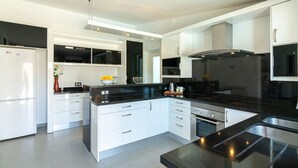 A modern kitchen with white cabinetry, a black countertop, and stainless steel appliances. - Villa 'Hortet' with Private Pool, Wi-Fi and Air Conditioning (Campos)