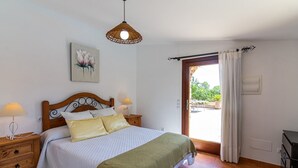 A bedroom with a bed, bedside lamps, a hanging light fixture, a painting, a window with curtains, and a view of the outdoors. - Villa 'Hortet' with Private Pool, Wi-Fi and Air Conditioning (Campos)