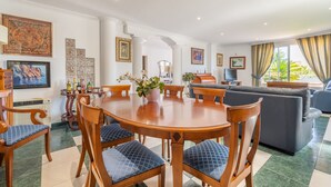Een eetgedeelte met een ronde tafel, stoelen en een bloevas.