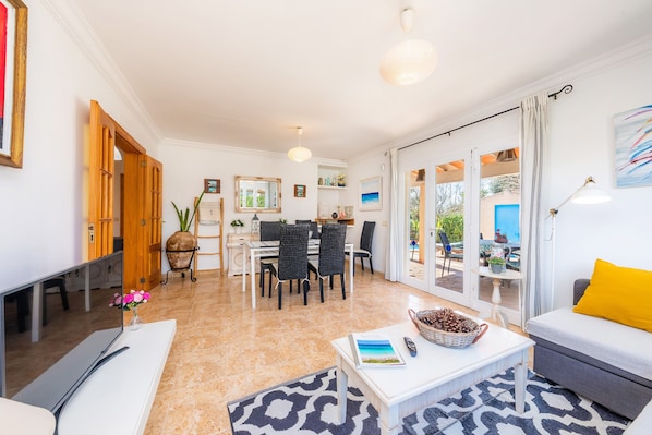 Amplia sala de estar con mesa de comedor, sofá y televisor.