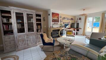 Een woonkamer met een open haard, een bank, een salontafel en een boekenkast.