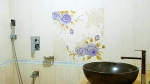 A bathroom with a large dark bowl on a countertop, a shower with a hose, and floral wall tiles. - Impulse Ocean View (Cox's Bazar)