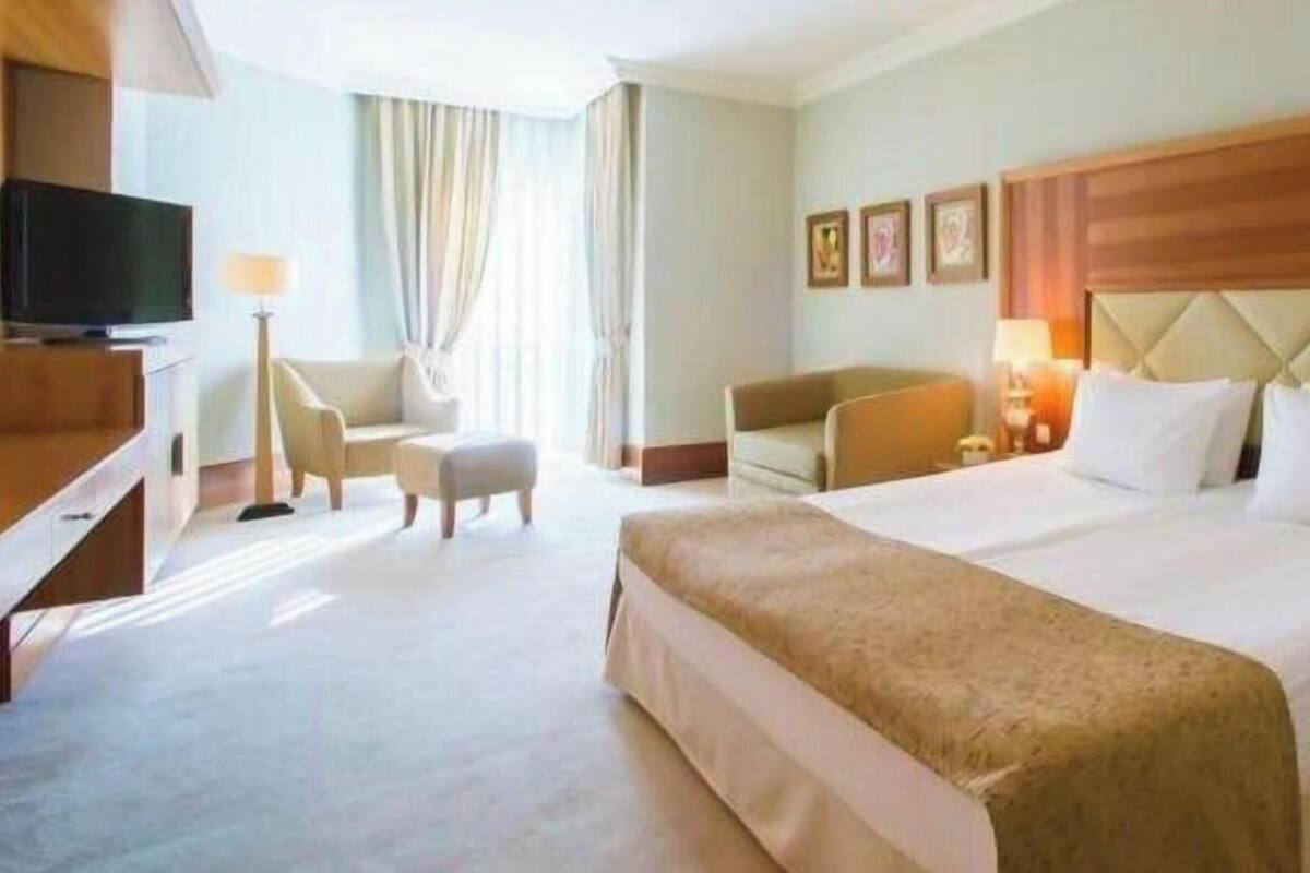 A hotel room with a large bed, a television, a desk, and a chair.