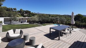 Une terrasse extérieure avec des meubles en osier, une table et un parasol.