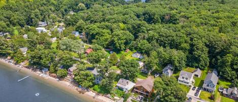 An aerial view of a coastal residential area with houses, a beach, and a lake.