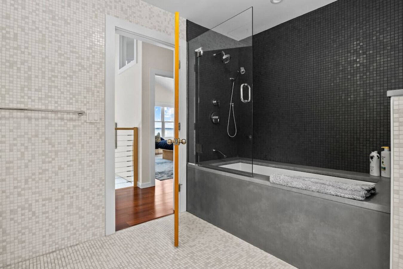 Un baño moderno con ducha de vidrio, una bañera grande y una ducha a ras de suelo.