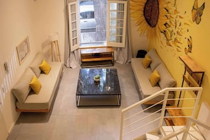 A modern living room with a sofa set, a coffee table, and a staircase.