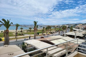 A coastal view with a promenade lined with palm trees, a marina with boats, and a mountain in the distance. - George's Poet Maisonette (Rethymno)