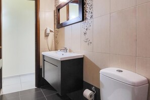 A bathroom with a white sink, dark cabinet, and a toilet. - George's Poet Maisonette (Rethymno)
