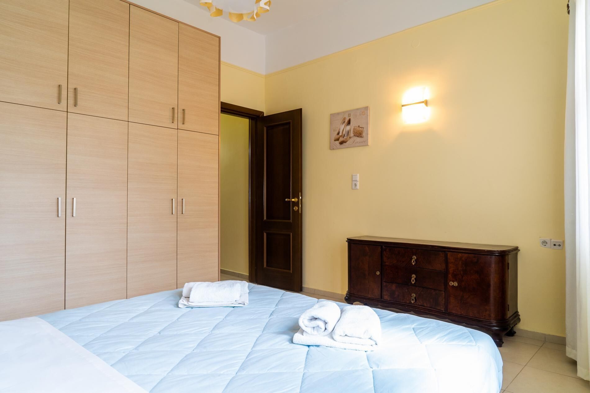 Une chambre à coucher comprenant un lit, deux serviettes, une armoire, un meuble et un luminaire fixé au mur.
