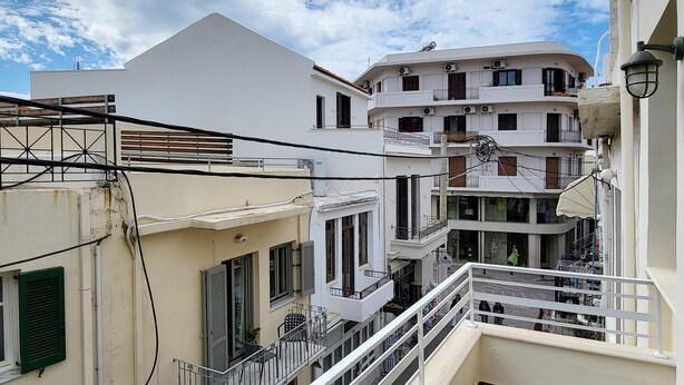 Un edificio residencial de varios pisos con balcones, una escalera y vista a la calle.