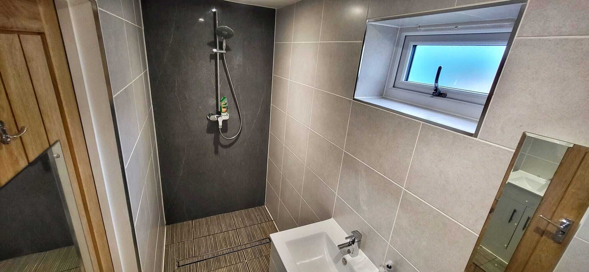 A modern bathroom with a shower, a sink, and a window.